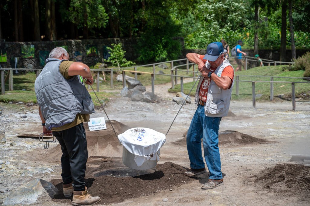 Traditional Cozido das Furnas volcanic stew being lifted from the steaming ground in Sao Miguel, Azores. Large pots cooking in geothermal holes at the edge of Furnas Lake