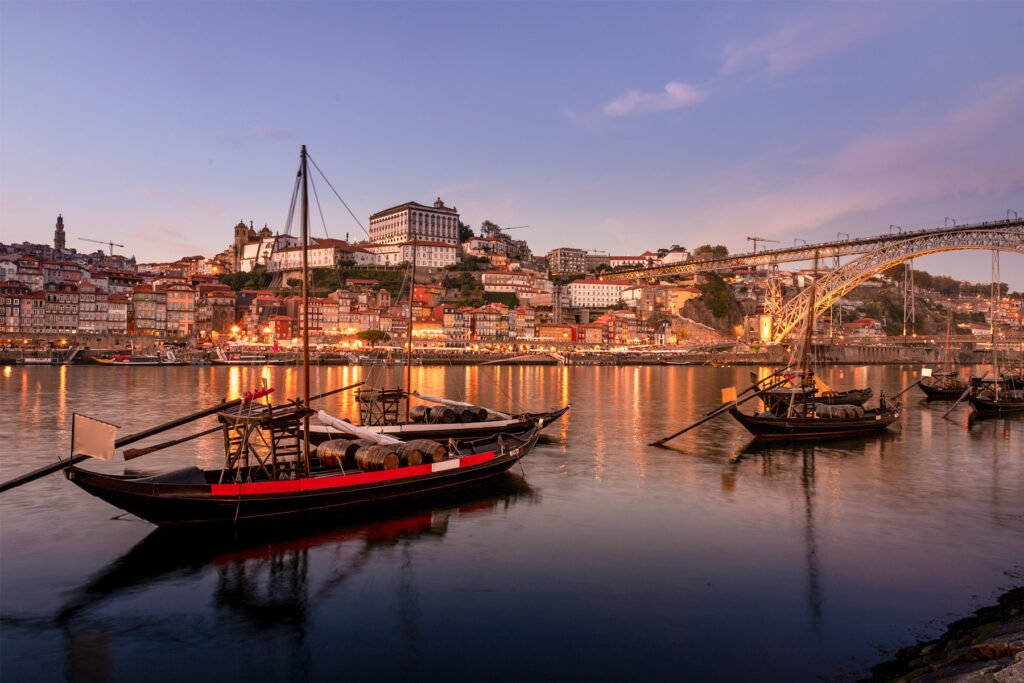 Rabelo boat on the Douro River with Porto’s Ribeira skyline at sunset, Portugal