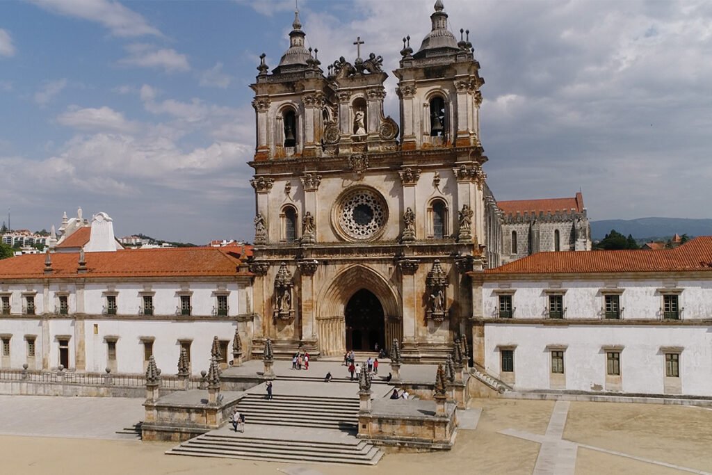 he imposing stone facade and central rose window of the Monastery of Alcobaça, a prime example of Cistercian Gothic in Portugal