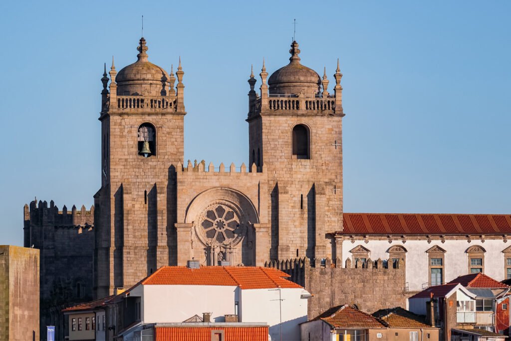 The twin bell towers and Romanesque facade of the Porto Cathedral overlooking the historic city center and red roofs.