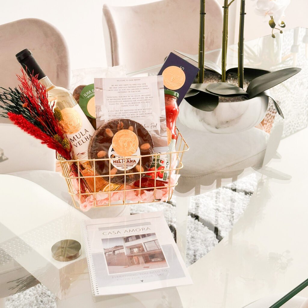 A personalized welcome tray at Casa Amora on a glass table, featuring a bowl of fresh grapes, blueberries, and strawberries, a glass jar with mixed nuts, a personalized 'Welcome Casa Amora' card, and a digital host guide on a screen in the background