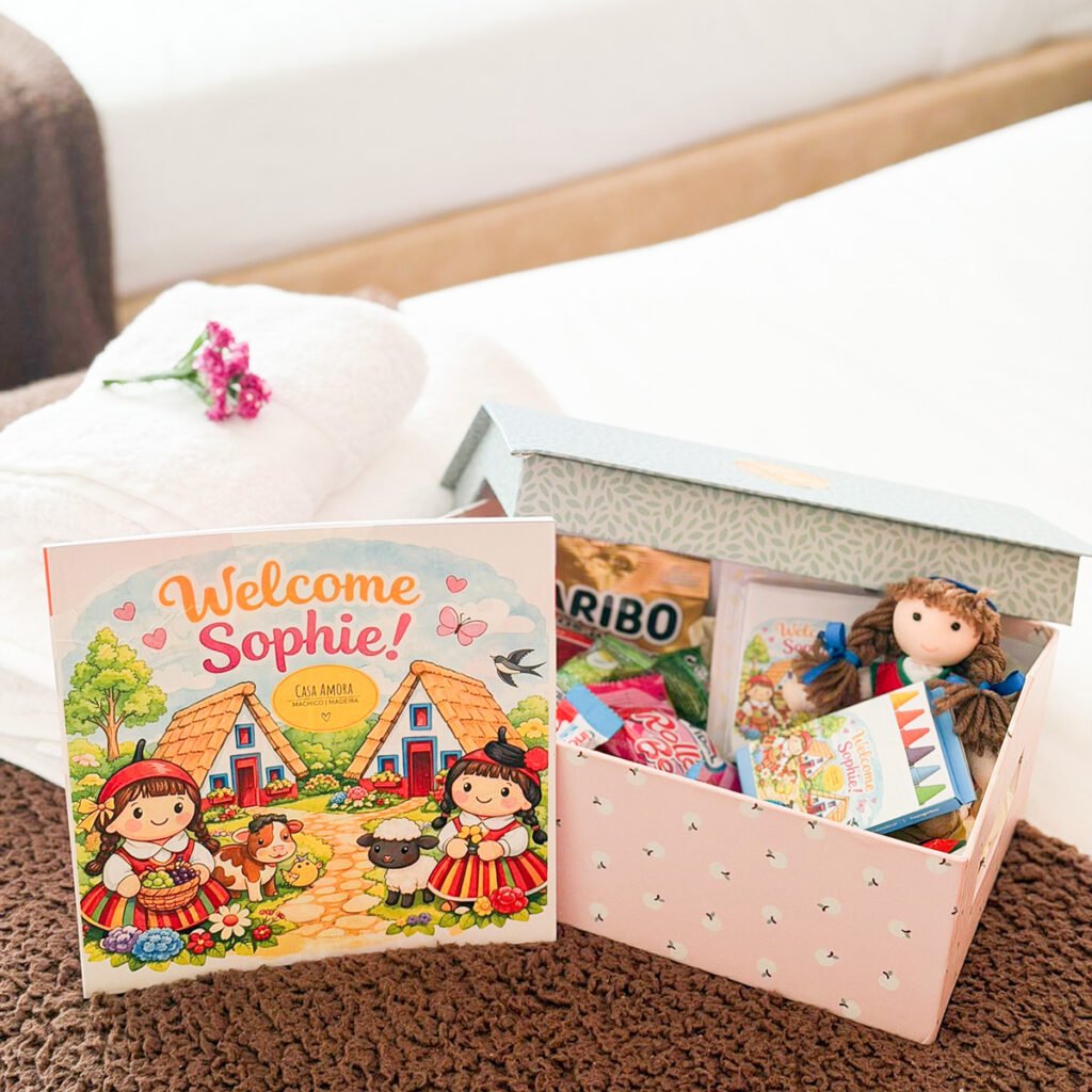 A children's welcome setup on a bed inside a family property in Caniço Madeira featuring fresh towels a colorful gift box with treats and an illustrated children's guidebook