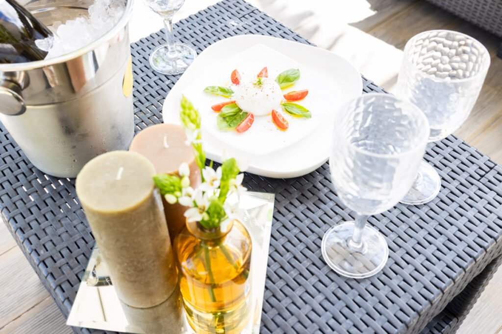 A close-up of an al fresco dining setup in a luxury house with an ocean view in Caniço showcasing premium glassware decorative candles and fresh local food
