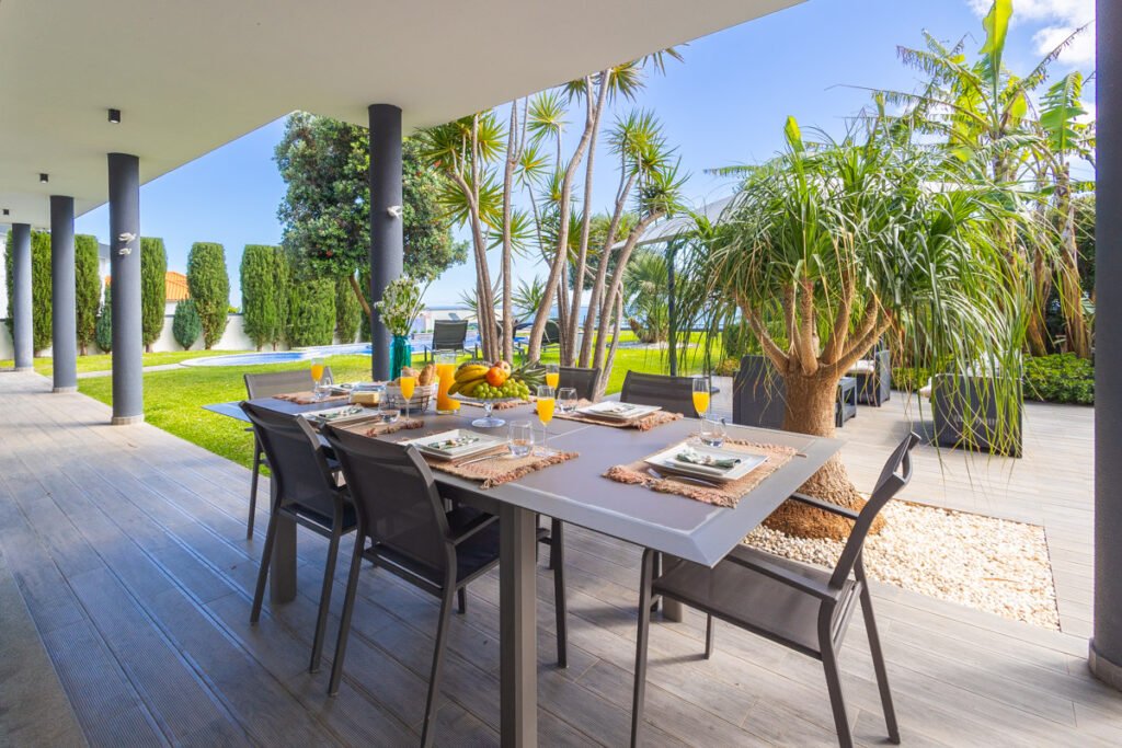 A beautifully set outdoor dining table on the terrace of the Caniço vacation rental, showcasing fresh Madeiran delicacies and a bespoke welcome surprise for guests