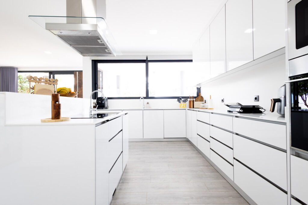 A state-of-the-art modern kitchen inside a certified luxury vacation rental in Madeira featuring minimalist white cabinets built-in ovens and high-end open-space countertops