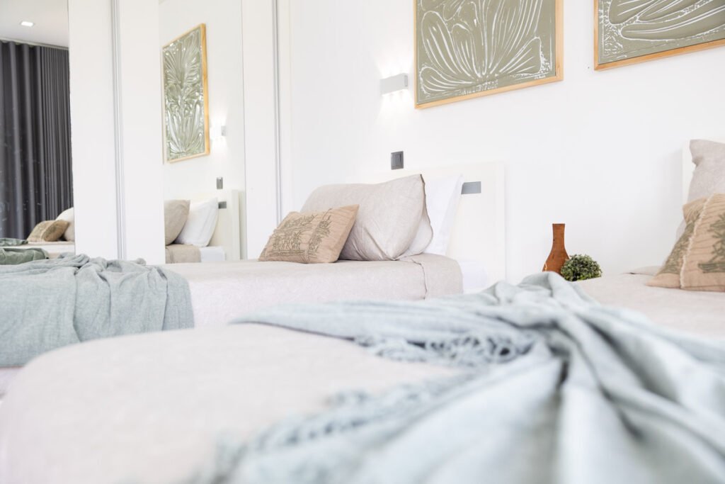 The second comfortable bedroom inside the certified AL Caniço property decorated with soft sage-green textiles twin beds minimal artwork and bright ambient lighting