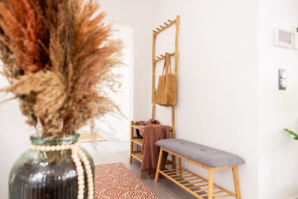 A bright minimalist entrance hallway of a luxury holiday home in Madeira featuring a sleek wooden console table decorated with dried plants and local artisan design items