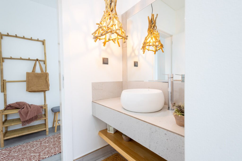 A premium contemporary bathroom interior in a certified AL Caniço property featuring warm backlit LED mirrors modern sleek fixtures and open storage shelving