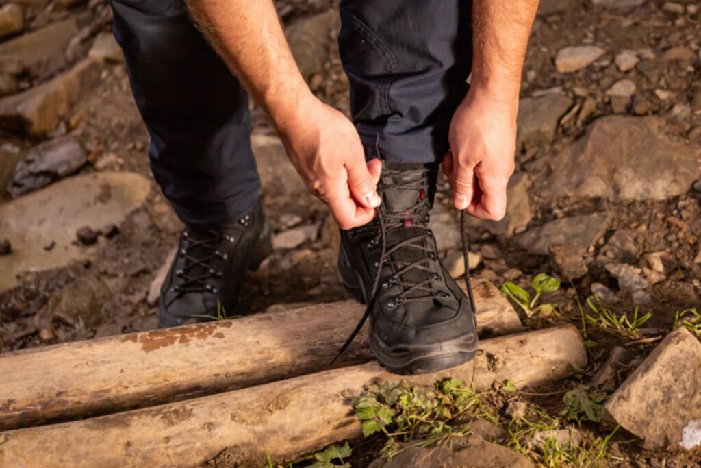 Close-up of a hiker tying shoe laces on black outdoor trekking boots and long mountain pants before hiking a trail in Madeira