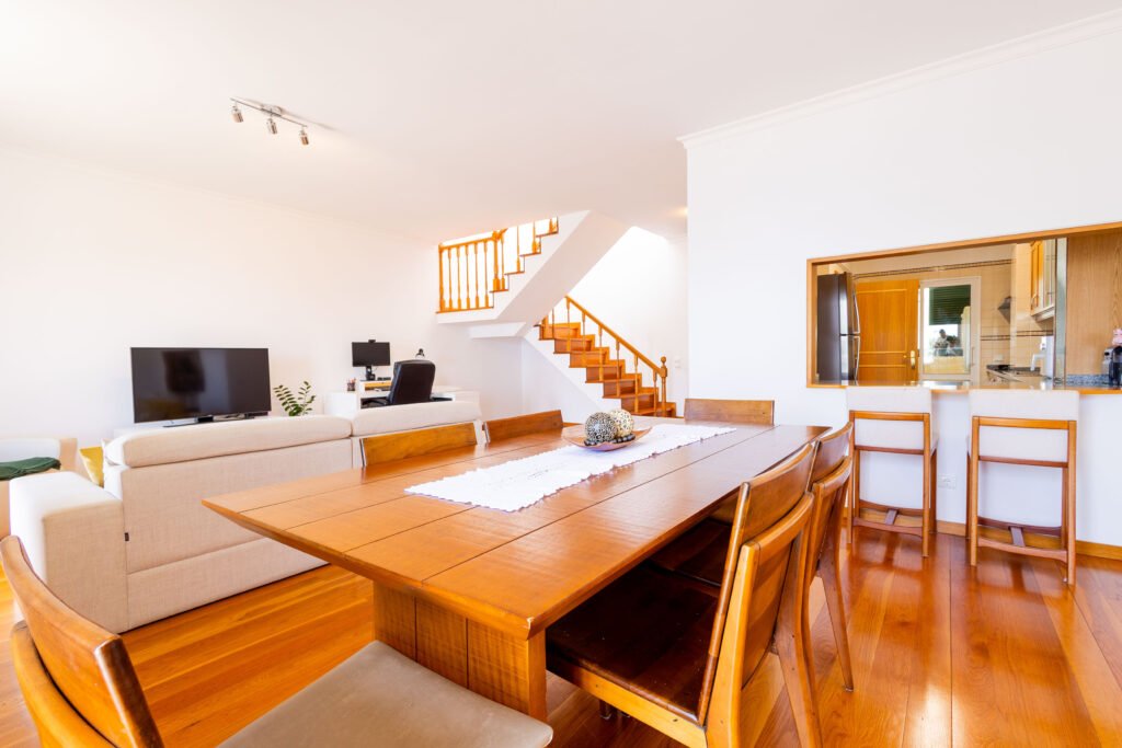 Bright dining space with wooden table and kitchen pass-through counter in luxury Funchal apartment